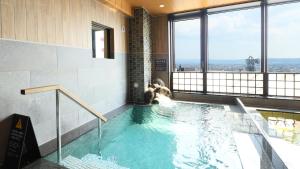 a swimming pool in a building with a view at Dormy Inn Aomori Natural Hot Spring in Aomori
