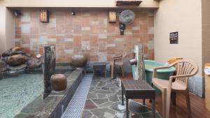 a pool with chairs and a hot tub in a room at Dormy Inn Aomori Natural Hot Spring in Aomori
