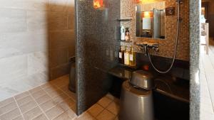 a bathroom with a shower with a toilet and a mirror at Dormy Inn Aomori Natural Hot Spring in Aomori