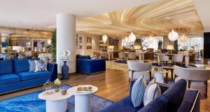 a lobby with blue couches and tables and a restaurant at Grand Hotel Brioni Pula, A Radisson Collection Hotel in Pula