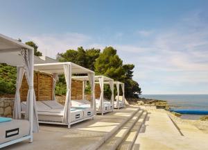 a row of white beds on a patio overlooking the ocean at Grand Hotel Brioni Pula, A Radisson Collection Hotel in Pula
