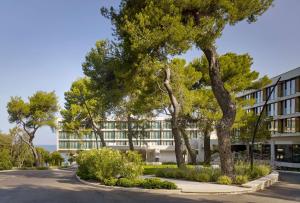 a building with trees in front of a street at Grand Hotel Brioni Pula, A Radisson Collection Hotel in Pula