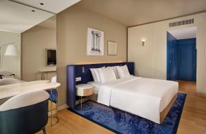 a bedroom with a large white bed and a desk at Grand Hotel Brioni Pula, A Radisson Collection Hotel in Pula