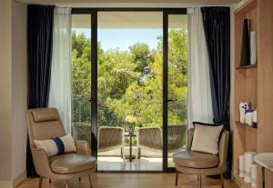 a living room with two chairs and a large window at Grand Hotel Brioni Pula, A Radisson Collection Hotel in Pula