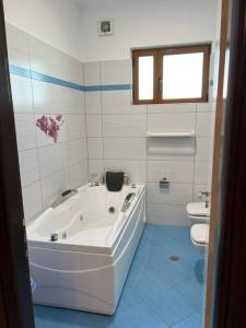 La salle de bains blanche est pourvue d'une baignoire et de toilettes. dans l'établissement Manga Apartments 3+1, à Gjirokastër