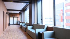 a row of chairs in a waiting room with windows at Dormy Inn Aomori Natural Hot Spring in Aomori