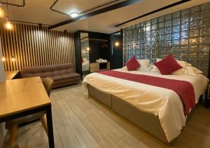 Hotel D' Leon في بوكارامانغا: غرفة نوم بسرير وطاولة واريكة
