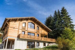 a wooden house with a balcony on top of it at Chalet La Tribu du Danay, neuf, 12 personnes in Saint-Jean-de-Sixt