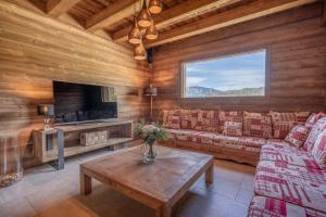 a living room with a couch and a tv at Chalet La Tribu du Danay, neuf, 12 personnes in Saint-Jean-de-Sixt