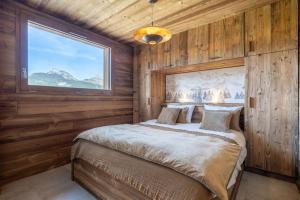a bedroom with wooden walls and a bed with a window at Chalet La Tribu du Danay, neuf, 12 personnes in Saint-Jean-de-Sixt