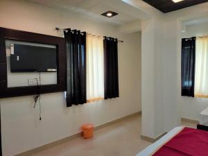 a bedroom with a flat screen tv on the wall at Hotel Goyal Palace in Agra