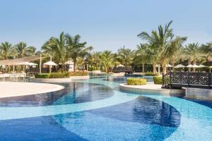 拉斯海瑪的住宿－哈伊馬角華爾道夫酒店，棕榈树和遮阳伞度假村的游泳池