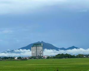 un grand bâtiment dans un champ avec des montagnes en arrière-plan dans l'établissement Room in Wyndham Thanh Thuy Hot Spring MyHome, à La Phu