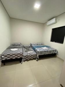a room with two beds and a flat screen tv at Flat Dona D - Prox da JK in Palmas
