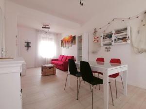 a living room with a white table and red chairs at Casa Magnolia in Aquiléia