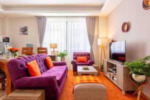 a living room with a purple couch and a tv at Cinnamon Residence in Nairobi