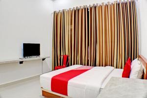 a bedroom with a bed and a tv and curtains at OYO 92945 Guest House Nusa Indah Syariah in Bandar Lampung