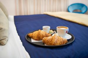 a plate with two cups of coffee and croissants on a bed at Firenze Rooms Cathedral B&B in Florence