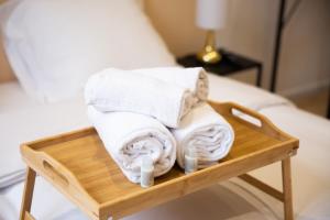 een stapel handdoeken op een houten blad op een bed bij NG SuiteHome - Lille I Roubaix Barbieux I Croix - Netflix - Wifi in Roubaix