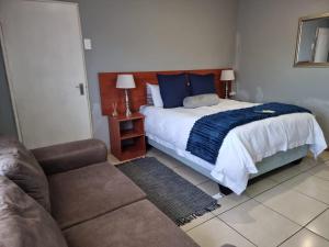 1 dormitorio con cama con almohadas azules y sofá en Monate BNB, en Kuruman