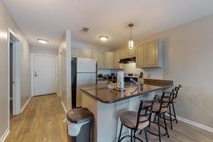 a kitchen with a counter with stools and a refrigerator at Perdido Dunes #20 in Orange Beach