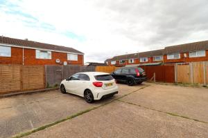 un coche blanco está estacionado en un estacionamiento en Luxury Apartment 5 mins to Luton Airport Sleeps 4 en Luton