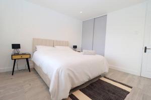 a white bedroom with a large bed and a table at Luxury Apartment 5 mins to Luton Airport Sleeps 4 in Luton