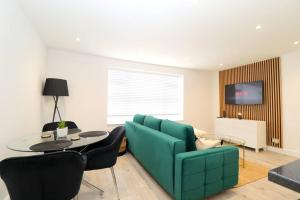 a living room with a blue couch and a table at Luxury Apartment 5 mins to Luton Airport Sleeps 4 in Luton