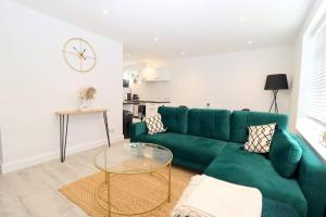 a living room with a green couch and a table at Luxury Apartment 5 mins to Luton Airport Sleeps 4 in Luton