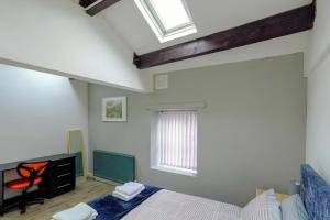 a bedroom with a bed and a desk and windows at Headingley 2 Bedroom first floor cottage flat Near Universities shops& Park in Leeds