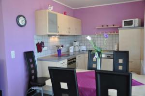 cocina con paredes de color púrpura, mesa y sillas en Ferienhaus Müritzperle, en Marienfelde