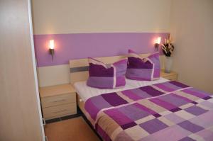 1 dormitorio con 1 cama de color púrpura y blanco con 2 almohadas en Ferienhaus Müritzperle, en Marienfelde