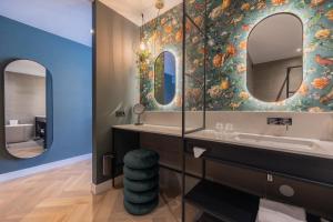 a bathroom with a sink and two mirrors at Van der Valk hotel Den Haag Wassenaar in Wassenaar