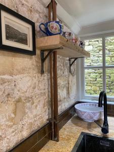 a kitchen with a sink and a stone wall at Linden Retreat in Brimscombe