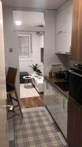 a kitchen with white cabinets and a table in a room at Apartment Mesic is 200 m away from the international airport in Sarajevo in Sarajevo