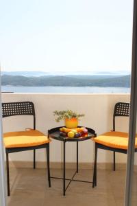 Dos sillas y una mesa con un bol de fruta. en Apartman Maslina, en Šibenik