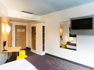 ein Hotelzimmer mit einem Bett und einem Flachbild-TV in der Unterkunft B&B Hotel Göttingen-City in Göttingen