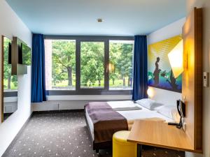 a bedroom with a bed and a desk and a window at B&B Hotel Göttingen-City in Göttingen