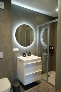La salle de bains est pourvue d'un lavabo blanc et d'une douche. dans l'établissement Seaside apartment Albatross, 16, à Ķesterciems