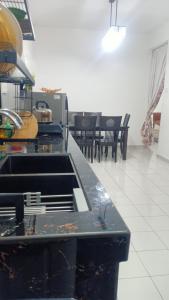 una cucina con piano di lavoro, tavoli e sedie di HOMESTAY BUDGET MASJID TANAH PERDANA a Masjid Tanah