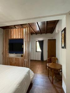 a bedroom with a bed and a table and a tv at Villa Kayu Padangbai in Padangbai