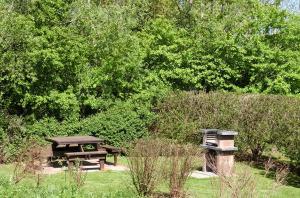 una mesa de picnic y un banco en un parque en Reetdachhaus Malve 3 im Feriendorf Puddeminer Wiek, en Puddemin