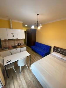 ein Schlafzimmer mit einem Bett, einem Tisch und einem blauen Sofa in der Unterkunft Студия с красивым видом на горы in Batumi
