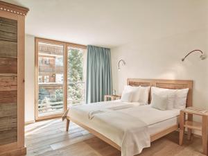 a bedroom with a large bed and a window at Firefly Luxury Suites in Zermatt