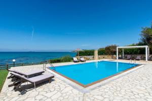 einen Pool mit zwei Liegestühlen und das Meer in der Unterkunft Beachfront Villa Victoras - With private beach in Sidari