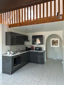 uma cozinha com armários pretos e piso em azulejo branco em Spacieux duplex à Folschviller 