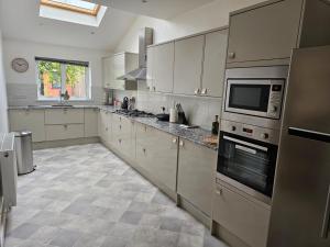 a large kitchen with white cabinets and a microwave at The Queen’s apartments in London