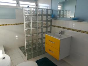 baño con lavabo y armario amarillo en Calme Villa en Sainte-Rose