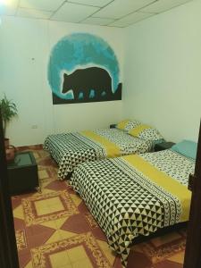 2 Betten in einem Zimmer mit Bär an der Wand in der Unterkunft Relajante, Mágico cautivador, tranquilidad y Paz - Piedechinche - Santa Elena - Hda El Paraíso. 