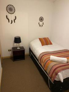 1 dormitorio con 1 cama y 1 mesa con lámpara en Cabaña Puerto Varas 1421 en Puerto Varas